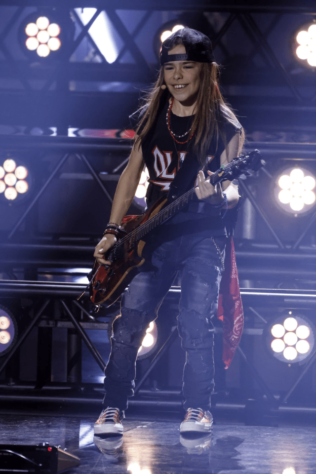 Girl playing electric guitar on stage.