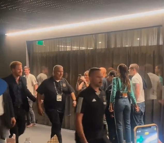 The moment Prince Harry, left, walks past Brooklyn and Nicola, far right,