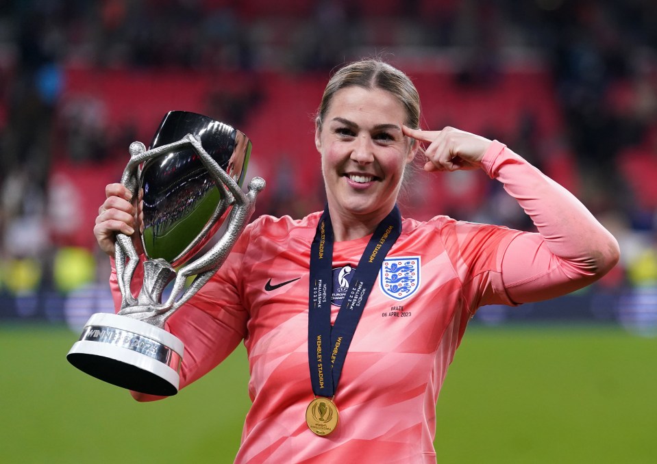 Mary Earps holding a trophy and medal.