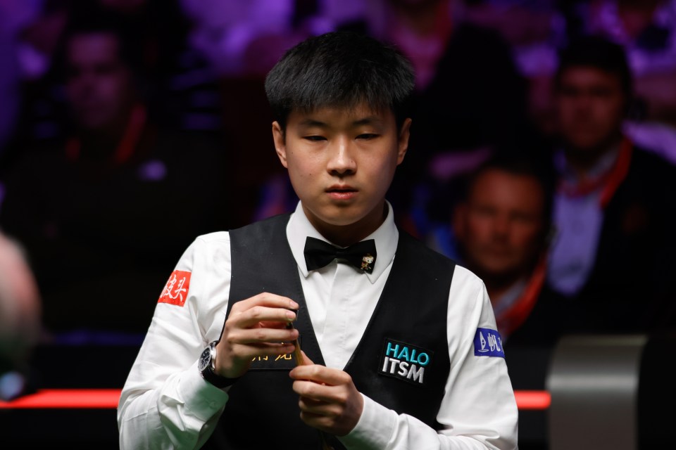 Zhao Xintong chalking his cue during a snooker match.