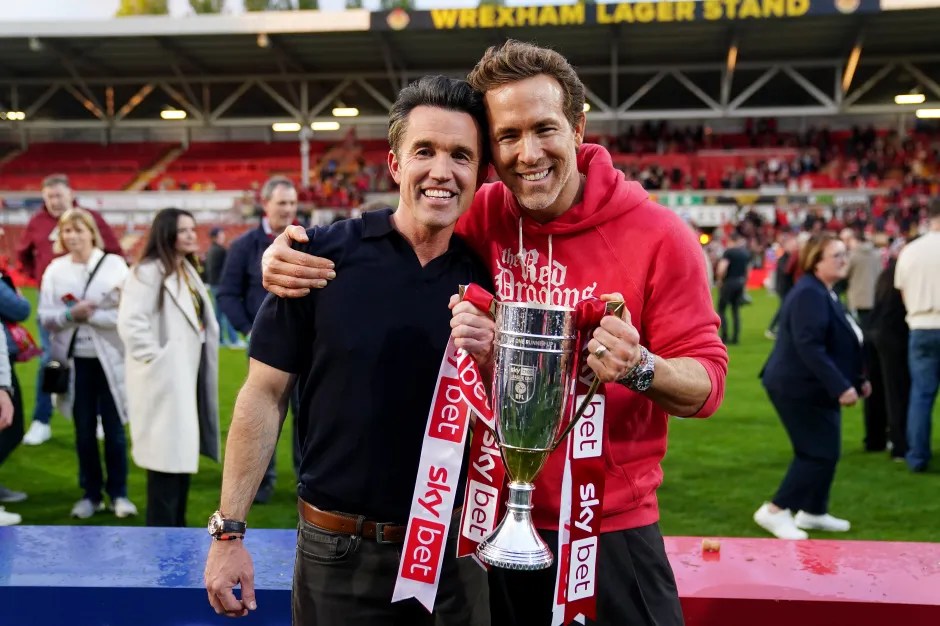 Two men holding a trophy at a soccer stadium.