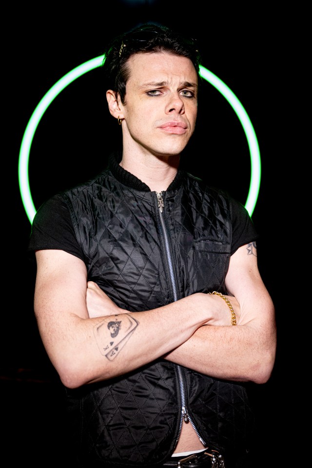 Yungblud backstage at a concert, arms crossed.