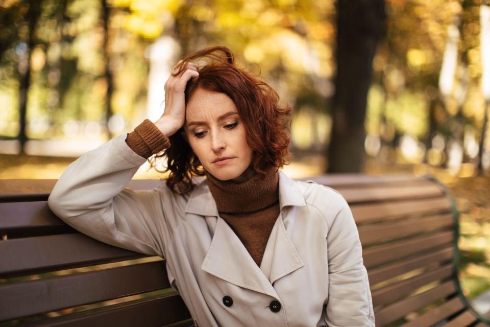 Sad young woman sitting on a park bench.