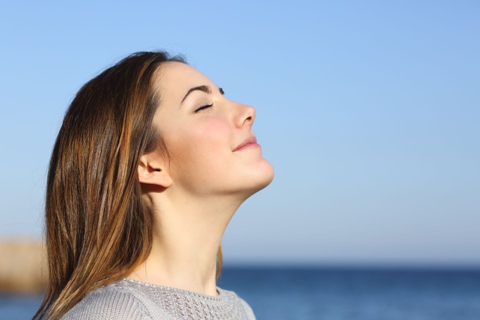 Woman breathing deeply by the ocean.