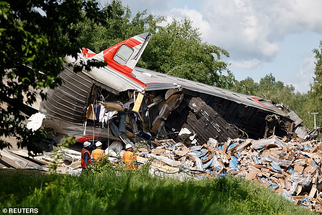 Specialists of emergency services gather near a destroyed train carriage at the scene, after a road bridge collapsed onto railway tracks due to an explosion in the Bryansk region, Russia, June 1, 2025