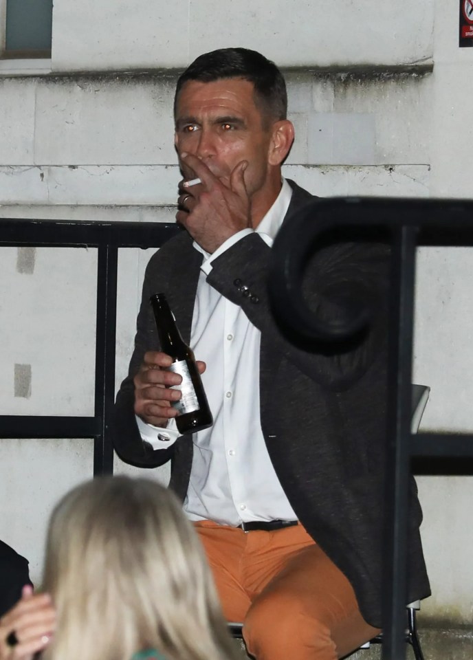 Man smoking and drinking beer outside.