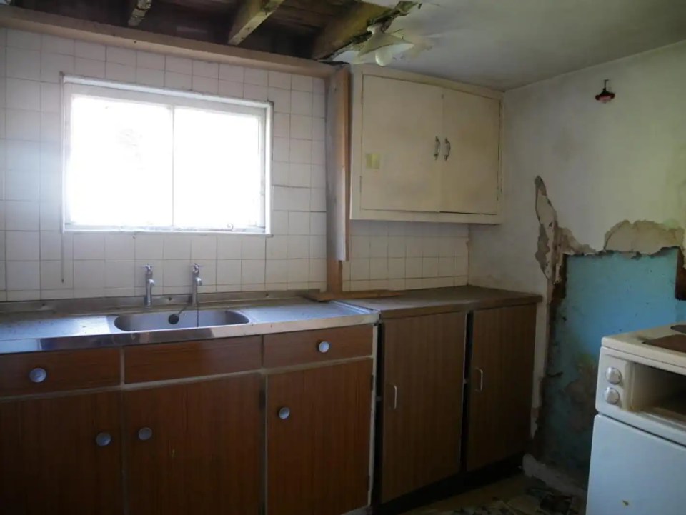 Damaged kitchen with wood cabinets and a stainless steel sink.