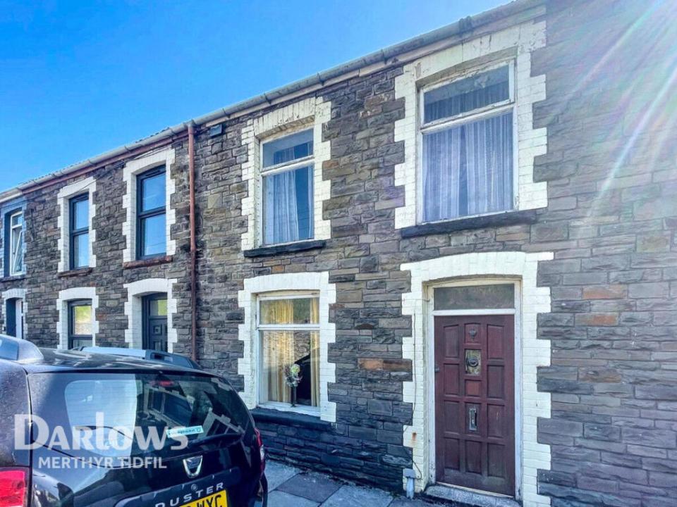 Stone terraced house with brown door.