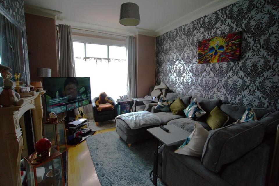 Living room with grey sectional sofa, TV, and skull artwork.