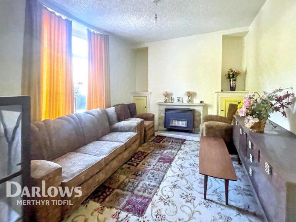 Living room with brown sofa, fireplace, and patterned rug.