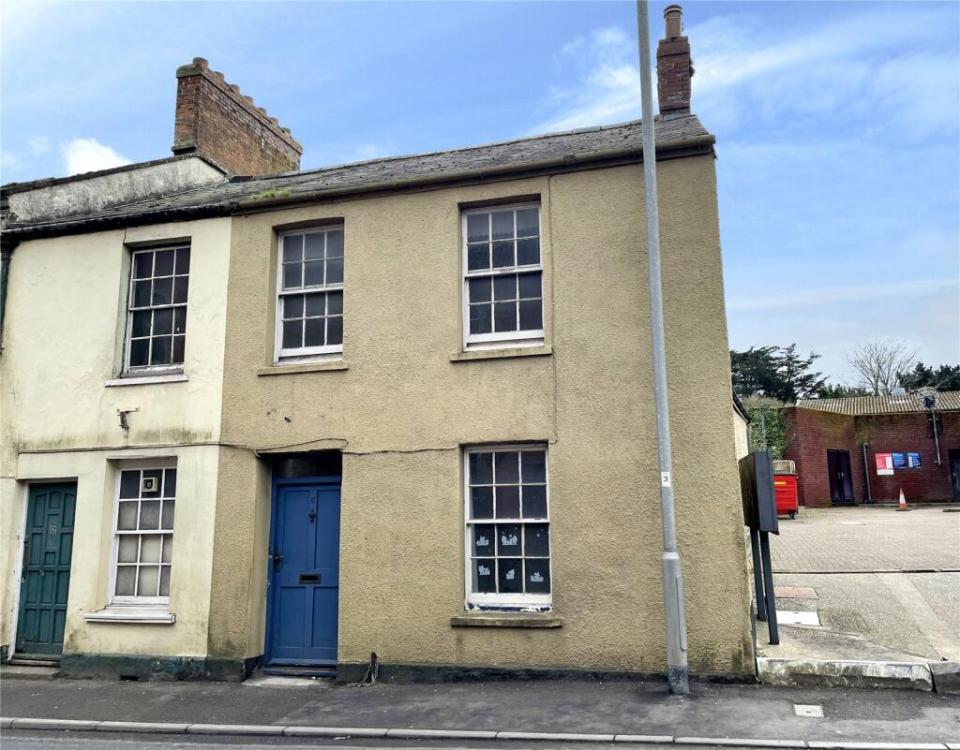 Two-story tan house with a blue door.