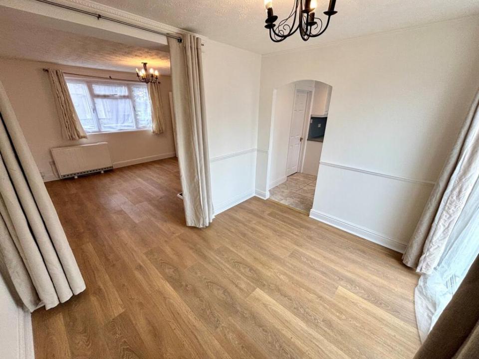 Dining room with light wood flooring and arched doorway to kitchen.