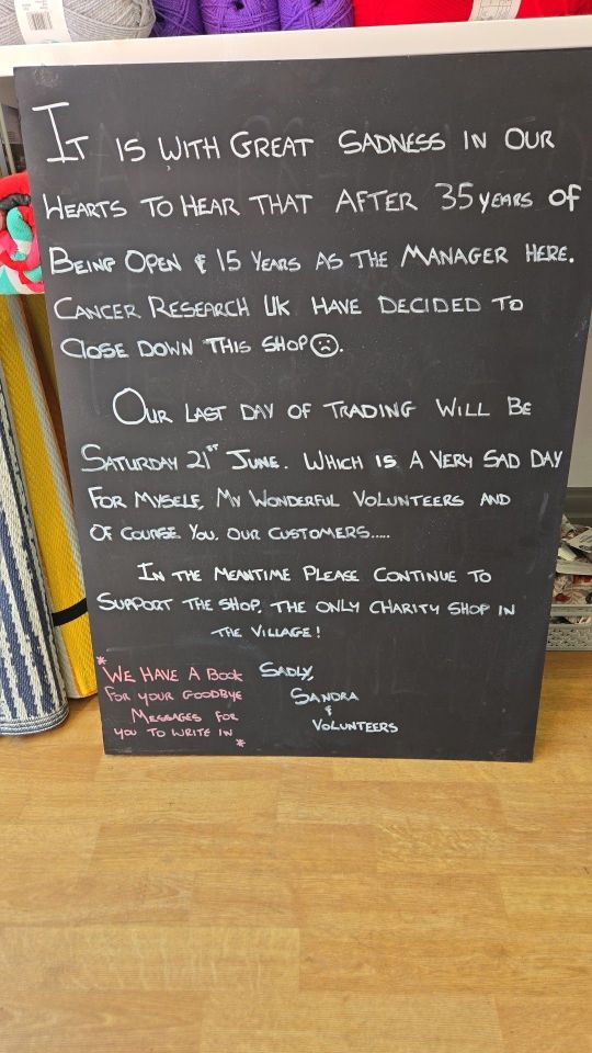 Chalkboard announcement of a Cancer Research UK charity shop closing after 35 years.