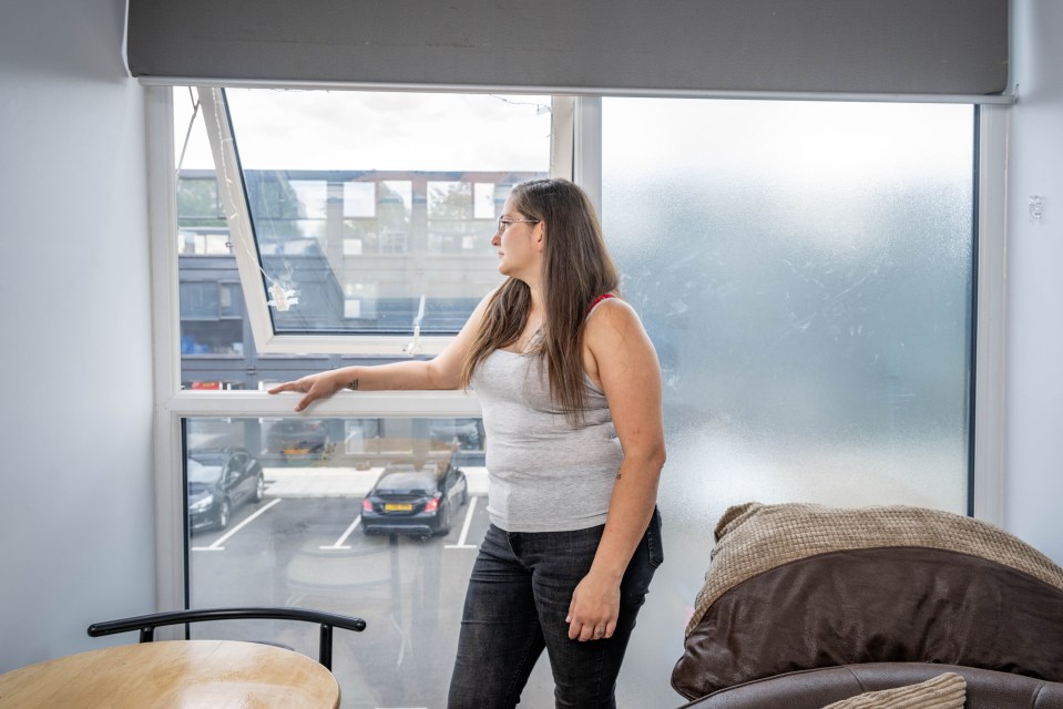 Woman standing by window in her shipping container home.