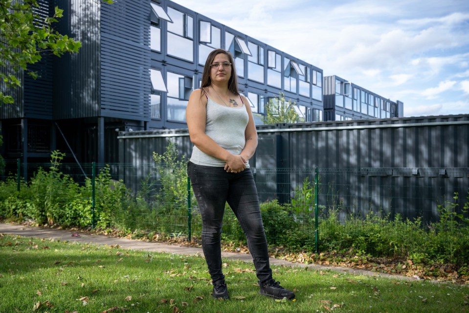 Woman standing outside her shipping container home.