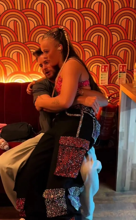 JoJo Siwa and Chris Hughes embracing backstage.