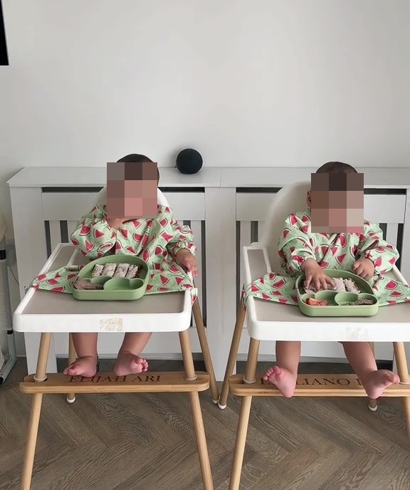 Ten-month-old twins eating breakfast in high chairs.