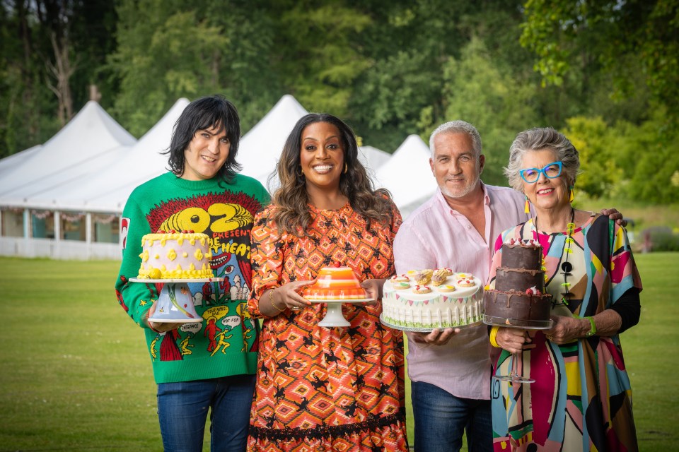 The Great British Bake Off judges and hosts posing with cakes and a dessert.