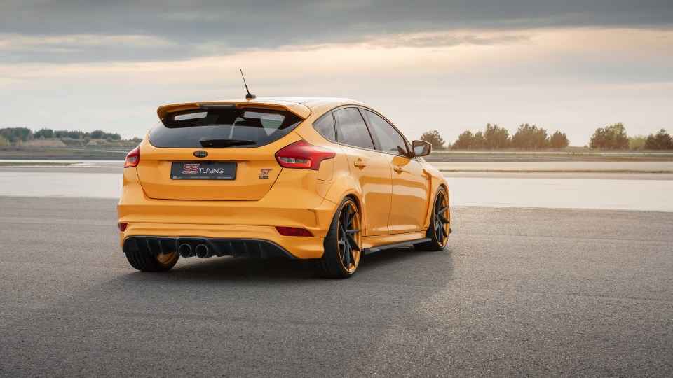 Rear three-quarter view of a yellow Ford Focus ST hatchback parked on asphalt.