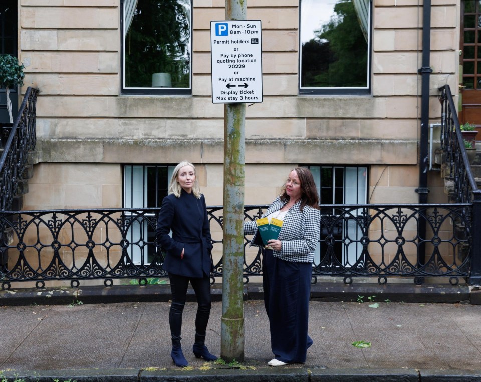 Two women standing by a parking sign, complaining about parking enforcement.