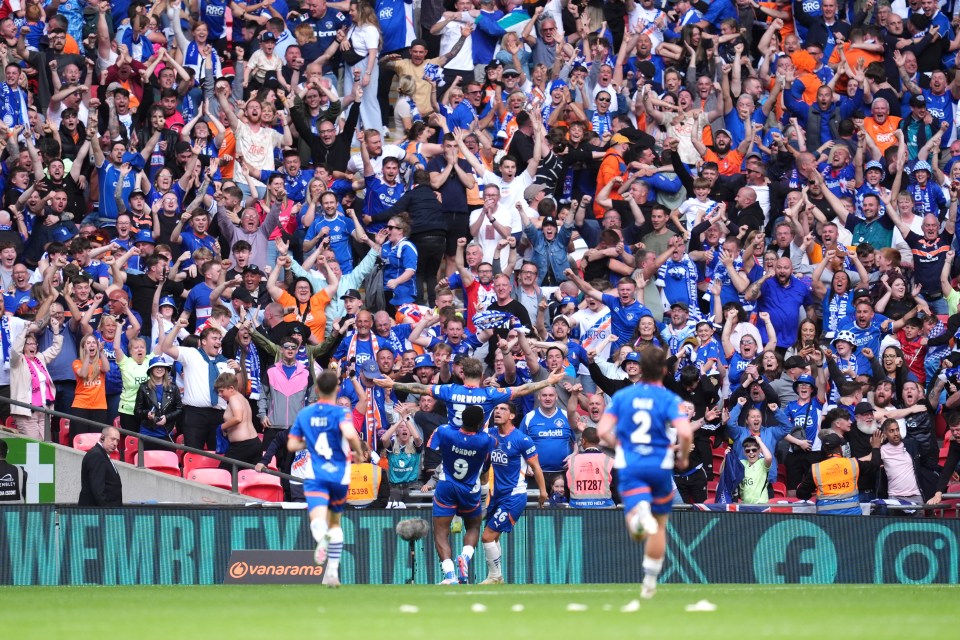 Oldham Athletic players celebrating a goal at Wembley Stadium, surrounded by cheering fans.