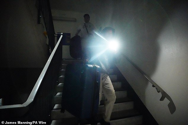 Security staff in Terminal 2 had to use the torches on their phones to see at night because of the total loss of power (Pictured: People using their torches in the Terminal 4 car park)