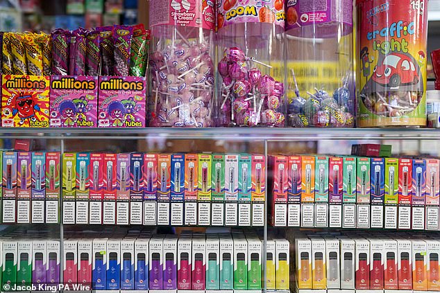 Disposable vapes of varying flavours on sale beneath children's sweets and lollipops in a store close to Birmingham -- January 29, 2024