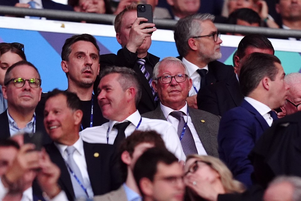 Gary Neville and Alex Ferguson in the stands at a soccer match.