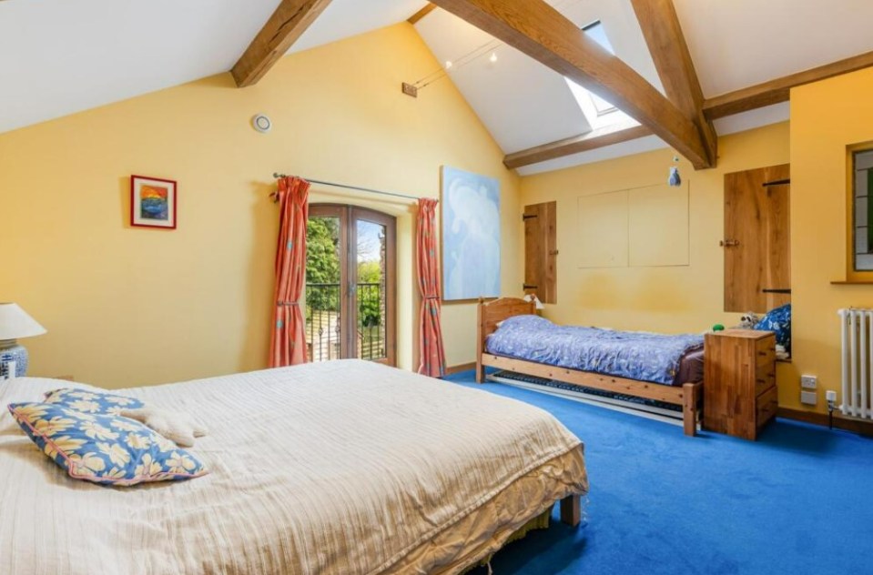 Bedroom with double bed and single bed, yellow walls, and blue carpet.