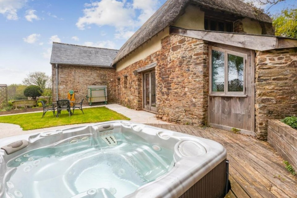Hot tub outside a stone barn.