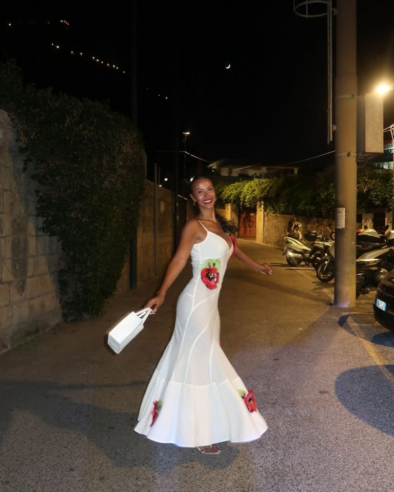 Maya Jama in a white maxi dress with red floral appliqués.