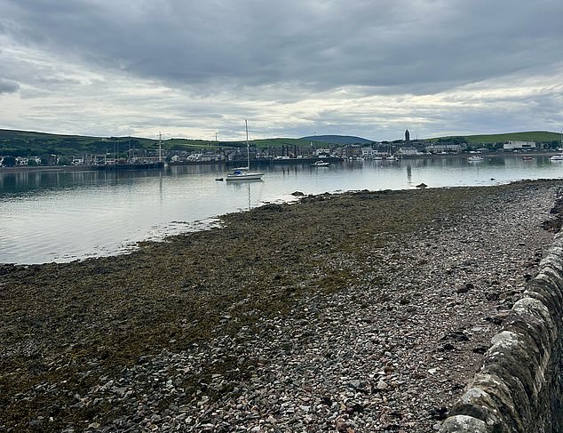 As you walk along the shore, you're met with a view of the small town, which is surrounded by rolling hills