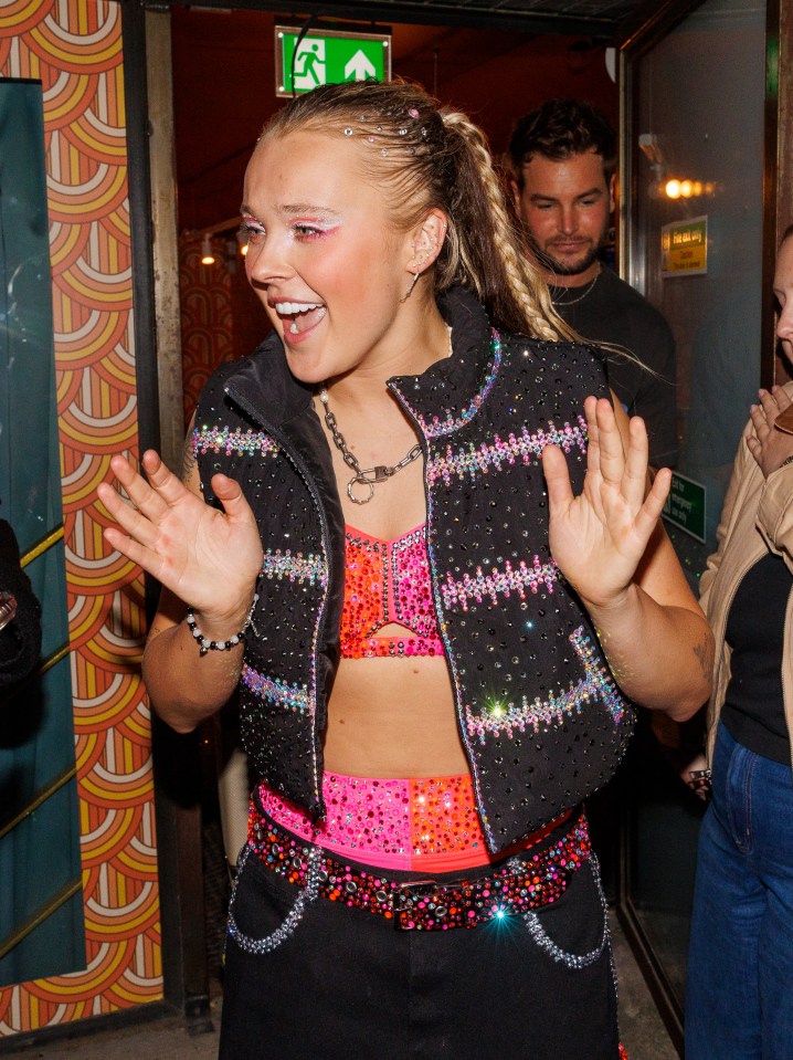 JoJo Siwa waving while leaving a building.
