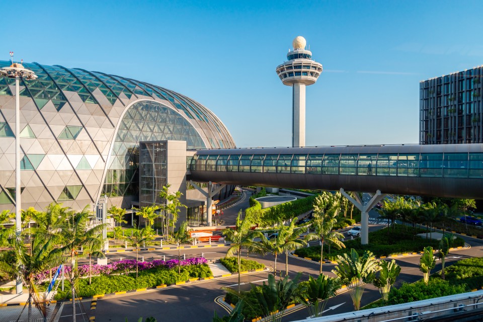 Changi Airport terminal with connecting bridge and air traffic control tower.