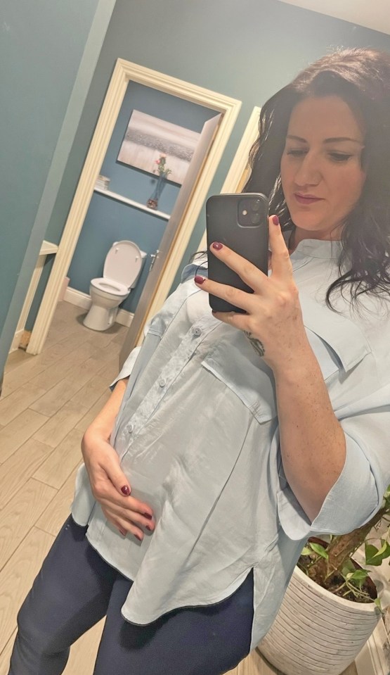 Pregnant woman taking a selfie in a restroom.