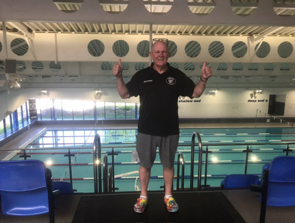 Man giving thumbs up by a swimming pool.