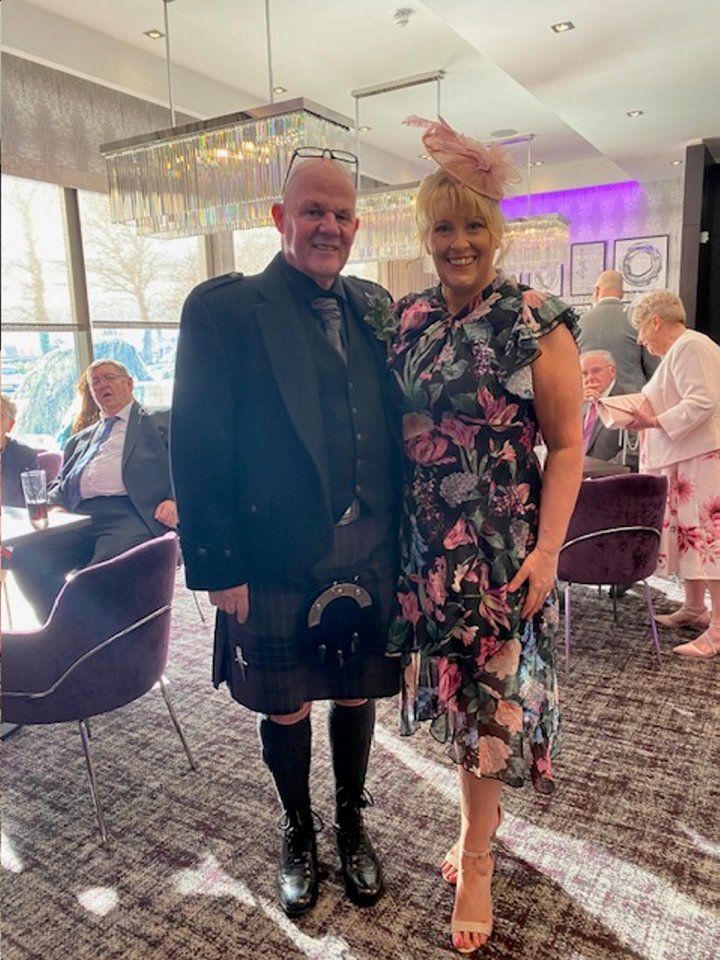 A man in a kilt and a woman in a floral dress pose for a photo.