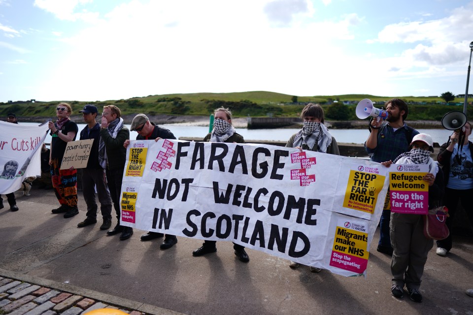 Protestors in Aberdeen, Scotland hold signs that read "Farage Not Welcome in Scotland."