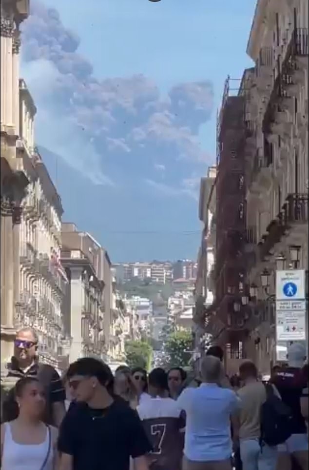 Crowds look on in shock as a ginormous ash cloud begins to cover the city of Catania