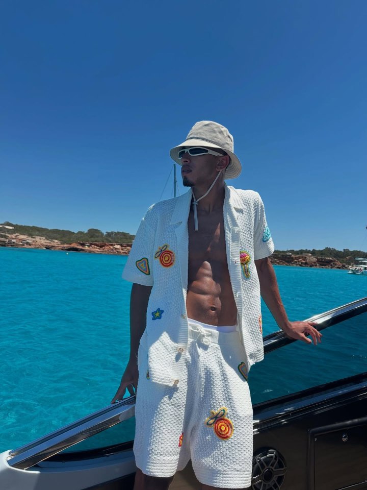 Man in white knit shorts and shirt on a boat.