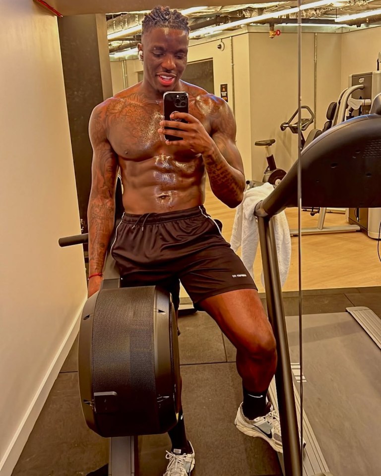 Shirtless man taking a selfie in a gym.