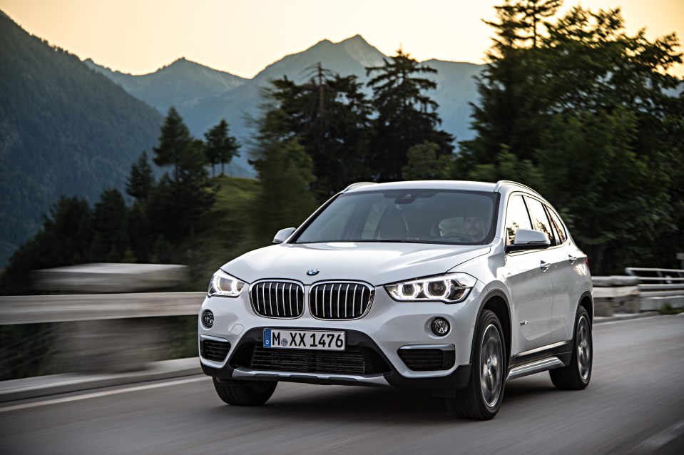 White BMW X1 driving on a mountain road.