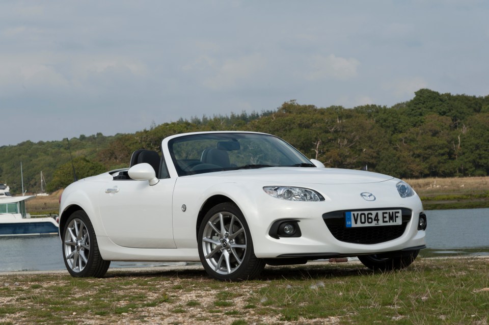 White Mazda MX-5 Roadster parked by the water.