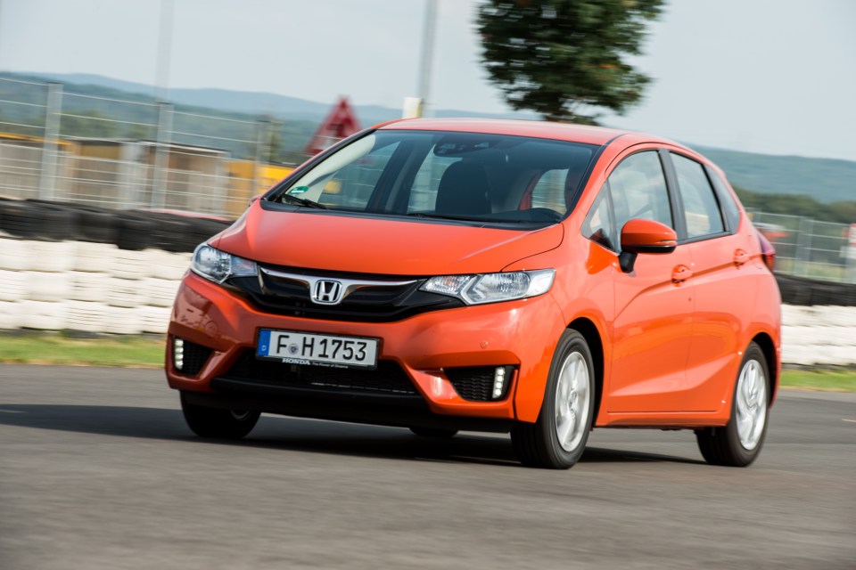 Orange Honda Jazz driving on a track.