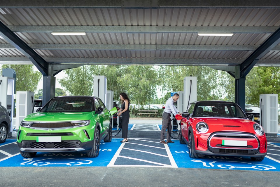 Two people charging electric cars at a charging station.