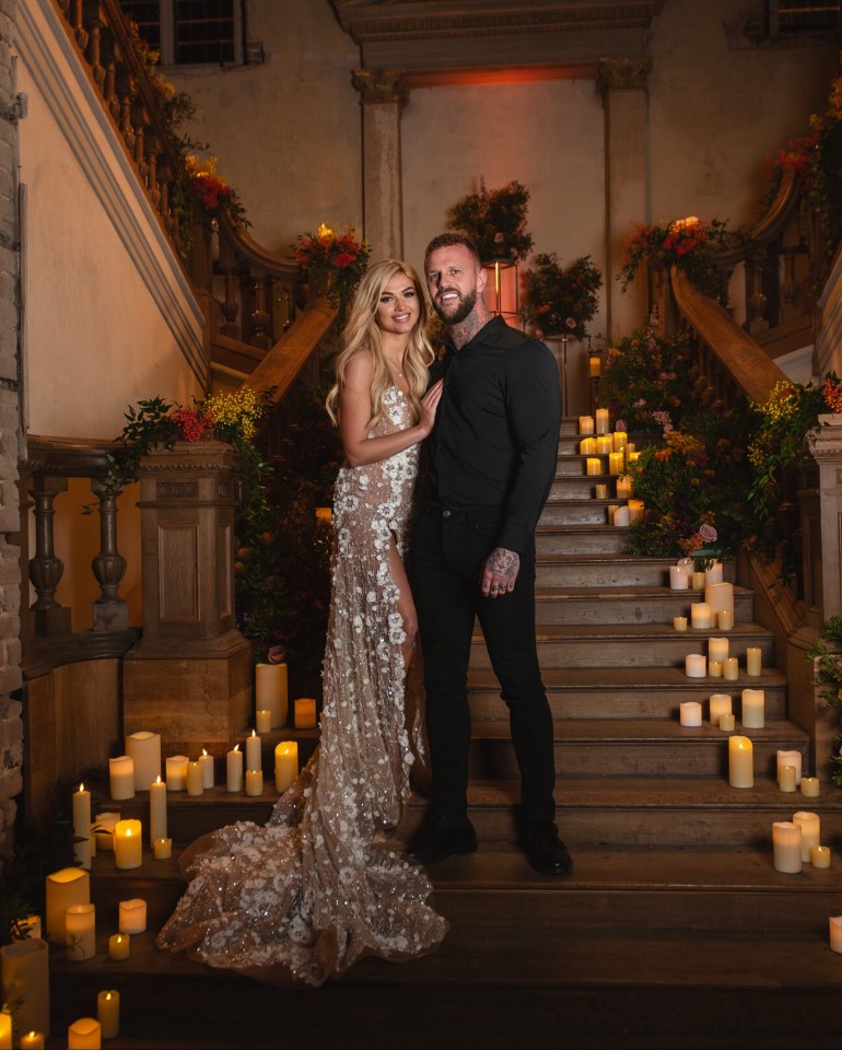 Couple posing on a staircase decorated with candles and flowers.