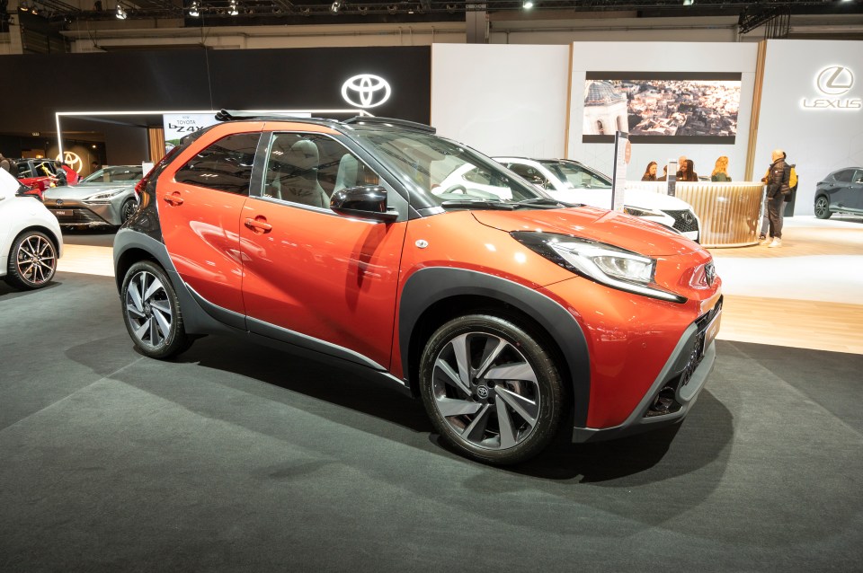 Orange Toyota Aygo X compact SUV at a car show.