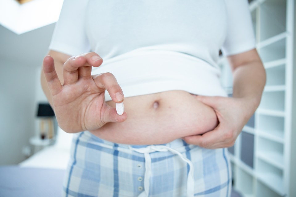 Overweight person holding an anti-obesity pill.