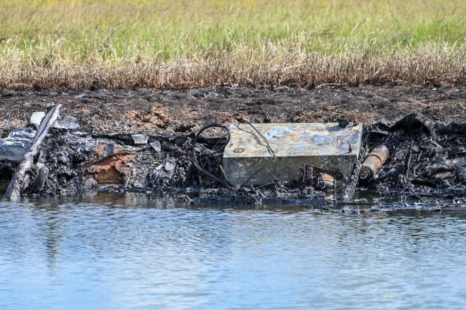 Burned debris near a body of water.