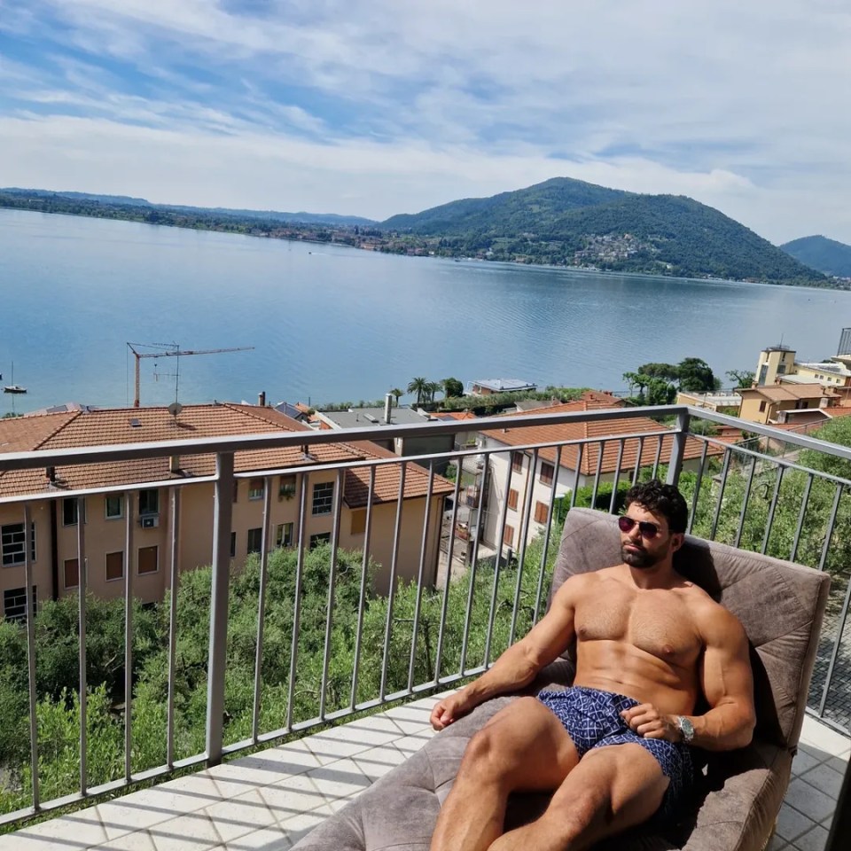 Man relaxing on a balcony overlooking a lake.